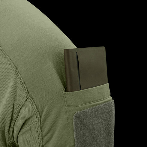 A green notebook is partially tucked into the sleeve pocket of the Condor Trident Short Sleeve Battle Top in olive green.