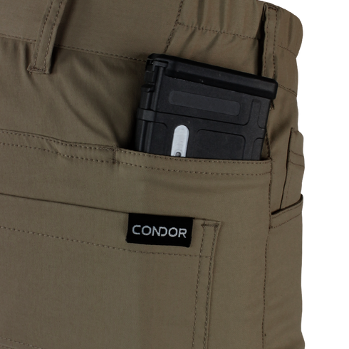 Close-up of a tan pocket on Condor’s Cipher Pants holding a partially visible black rifle magazine against a plain background.