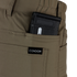 Close-up of a tan pocket on Condor’s Cipher Pants holding a partially visible black rifle magazine against a plain background.