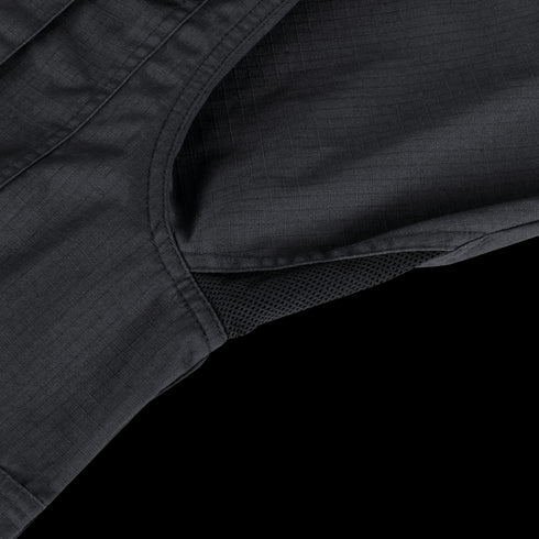 Close-up of the Condor Tac-Pro Shirt | SALE in black, showing a mesh vent panel and stitched seam detail, laid on a green and beige striped surface.