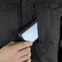 A person slips a smartphone into the front pocket of a dark Condor Tac-Pro Shirt.