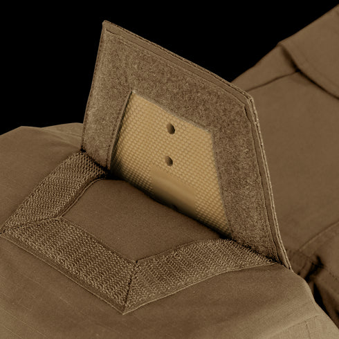 Close-up view of Condor Paladin Tactical Pants in tan, featuring a ballistic plate partially inserted into a pocket with hook-and-loop fasteners.