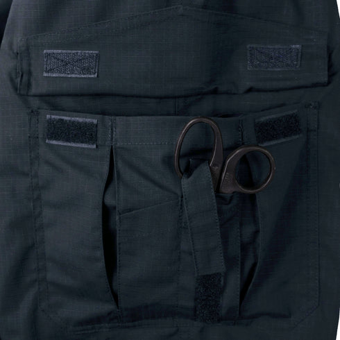 A pair of black trauma shears is partially tucked into a dark utility pocket with Velcro flaps on the Condor Women's Protector EMS Pants.