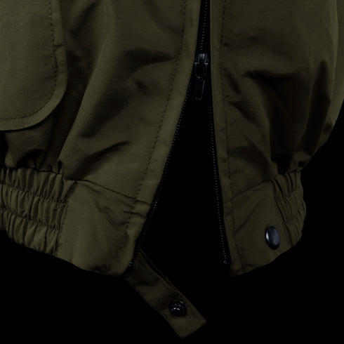 Close-up of the Condor Guardian Duty Jacket | SALE in olive green, featuring a partially unzipped zipper, elastic waistband with stitching, snap button, and hanging strap.