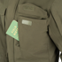 A green Field Notes notebook partially tucked into the chest pocket of a Condor Aegis Waterproof Parka.