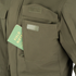 A green Field Notes notebook partially tucked into the chest pocket of a Condor Aegis Waterproof Parka.
