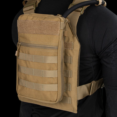 Person wearing the Condor Tidepool Hydration Carrier—a tan vest with zippered front pouch and MOLLE webbing—over a black long-sleeve shirt; perfect for bushcraft or range use.
