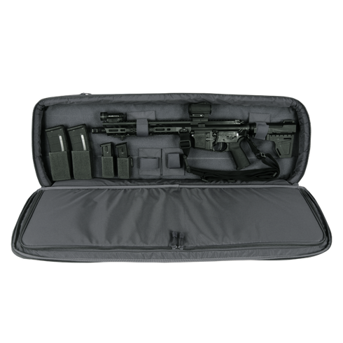 A black rifle with scope and magazines is stored in the Condor 36" Javelin Rifle Case, a padded gray carrying case with accessory compartments.