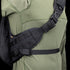 A close-up of a person wearing the Condor Elite Sector Sling Bag 18L by Condor, featuring black tactical straps with clips and padding, over an olive green long-sleeve shirt.