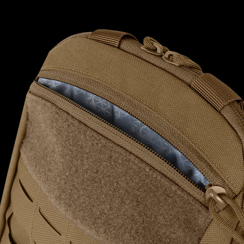 Close-up of the Condor LCS Tidepool Hydration Carrier, a tan backpack with military-inspired design, partially unzipped to reveal its patterned gray interior lining and rugged fabric construction.