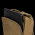 A tan Condor Prime Pack 21L tactical backpack with a partially open zipper shows a black laptop inside the main compartment.