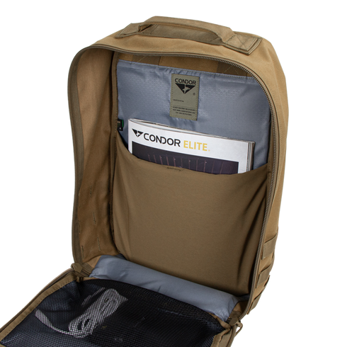 Open tan Prime Pack 21L by Condor showing inner pocket with booklets labeled Condor Elite and Condor, plus a mesh zippered compartment below.