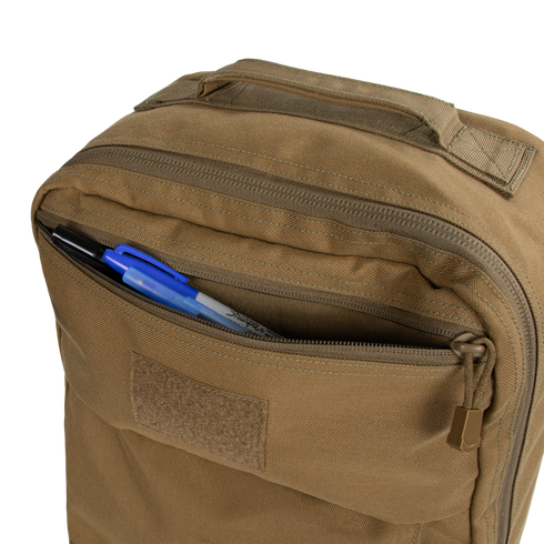 The Condor Prime Pack 21L, in tan, has a front zippered pocket partially open, revealing a black pen, blue pen, and a marker inside.