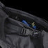 A close-up of the Condor Aero Roll-Top Backpack 25L reveals its interior, featuring a strap, buckle, and a partially visible blue object inside.