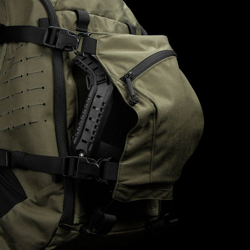 The Condor Nomad Backpack 25L in olive green features a partially open zippered side pocket showing a black hard plastic handle inside—perfect for military or law enforcement professionals.