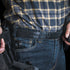 A person wearing a plaid shirt and jeans with a Condor Inner Belt, carrying a holstered handgun on their waistband, resembles an off-duty law enforcement officer.