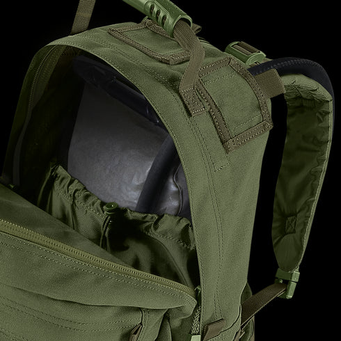 A close-up of the Condor Medium Assault Backpack 30L in olive green shows its top compartment unzipped, revealing an internal hydration bladder.