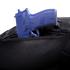 A blue training handgun is partially tucked into the zippered pocket of the Condor Ambidextrous Sling 27L, a black tactical bag made with mesh material.