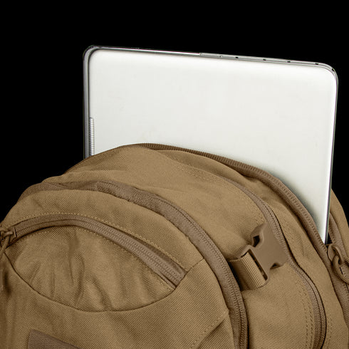 A silver laptop partially tucked into the main compartment of a brown Condor Commuter Backpack 26L.