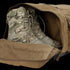 A pair of tactical camouflage military boots placed inside an open Condor Colossus Duffle Bag 60L.