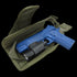 A blue training pistol with a mounted flashlight sits inside an open green Condor Tornado Tactical Leg Holster - Left Hand, which features a secure retention system for safety.