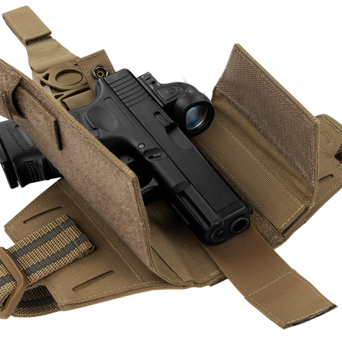 A black handgun with an optic sight is stored in a Condor LCS RDS Leg Holster, featuring tan color, straps, and Velcro flaps, displayed on a white background.