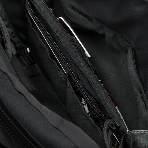 Close-up of the Condor Tech Pouch in MultiCam Black, displaying multiple zippered compartments and pockets with partially visible items inside.