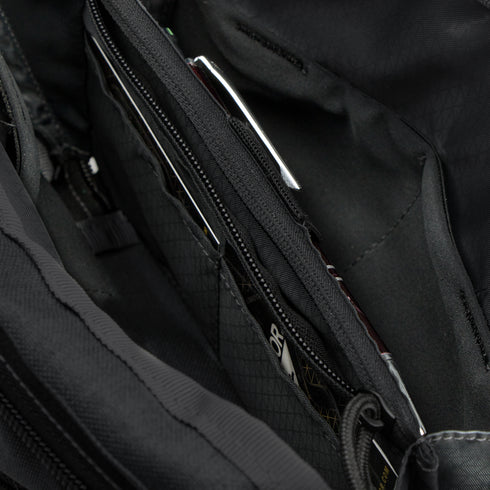 Close-up of the Condor Tech Pouch in MultiCam Black, displaying multiple zippered compartments and pockets with partially visible items inside.