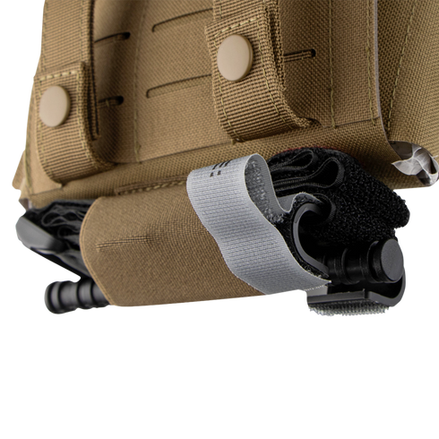 Close-up of the Condor Micro TK Pouch Gen II, a tan tactical vest accessory, with a black tourniquet secured by a gray strap in its designated holder pocket.