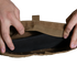 Two hands open a tan Enforcer Releasable Plate Carrier by Condor, revealing black interior details and MOLLE webbing against a white background.