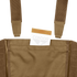 A tan envelope is partially tucked into the front pocket of a Condor LCS VAS Harness Kit, a brown utility vest featuring visible straps, often used by military personnel or at shooting ranges.