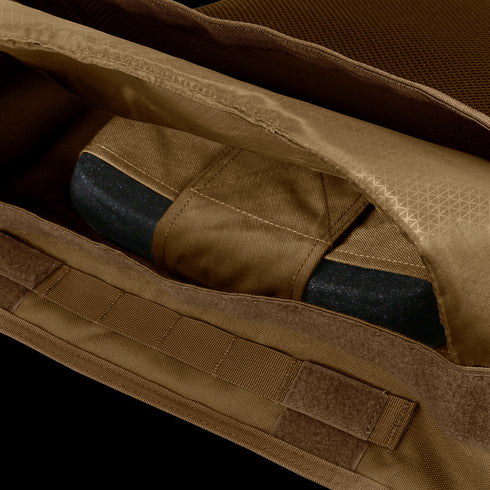 A close-up view of the Condor EXO Plate Carrier Gen II in brown fabric with an open zipper, showing a partially enclosed black object inside.