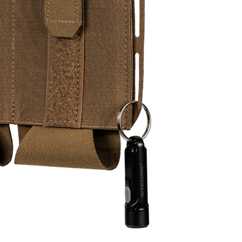 A small black flashlight on a keyring is attached to the brown fabric loop on the side of the Condor VAS Flex Placard tactical pouch.
