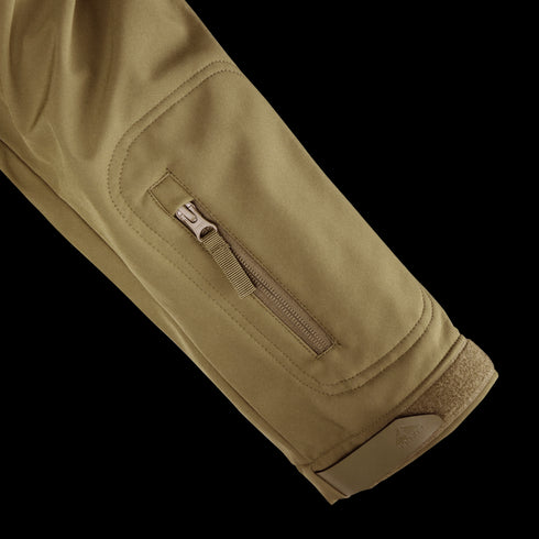 A close-up of the Condor Summit Zero Softshell Jacket in khaki shows its sleeve with a zippered pocket and hook-and-loop fastener at the cuff.