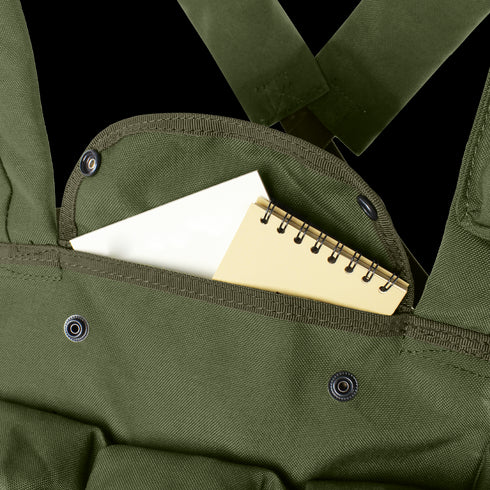 A small spiral notebook partially tucked into the front pocket of a Condor 7-Pocket Chest Rig in olive green, featuring metal snap buttons.