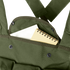 A small spiral notebook partially tucked into the front pocket of a Condor 7-Pocket Chest Rig in olive green, featuring metal snap buttons.