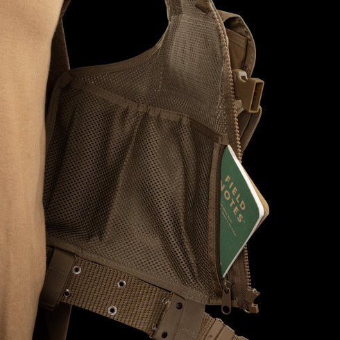 A green Field Notes notebook is partially tucked into the mesh pocket of a Condor Elite Tactical Vest, designed for Military or Law Enforcement professionals.