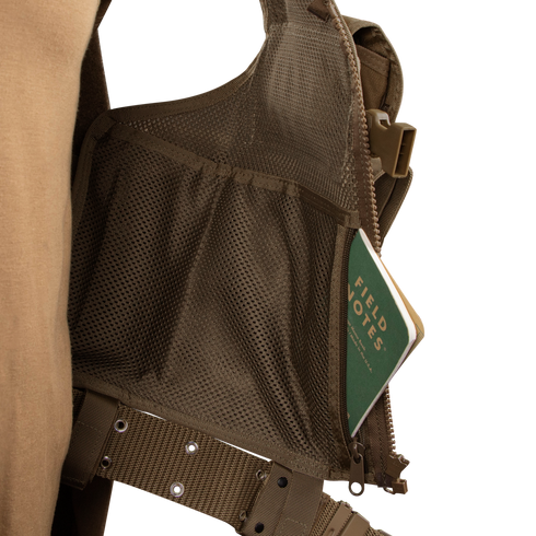 A green Field Notes notebook is partially tucked into the mesh pocket of a Condor Elite Tactical Vest, designed for Military or Law Enforcement professionals.