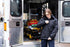 A person stands outside an open ambulance, zipping up a Condor Guardian Duty Jacket | SALE. The ambulance interior and a stretcher with medical supplies are visible behind them.