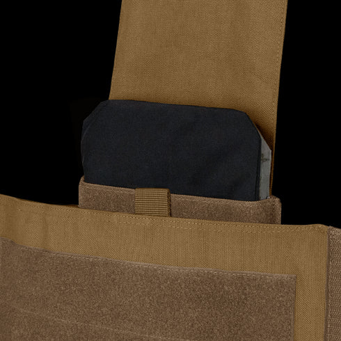 A close-up of a black ballistic plate partially inserted into the pocket of a tan Condor Modular Operator Plate Carrier Gen II.