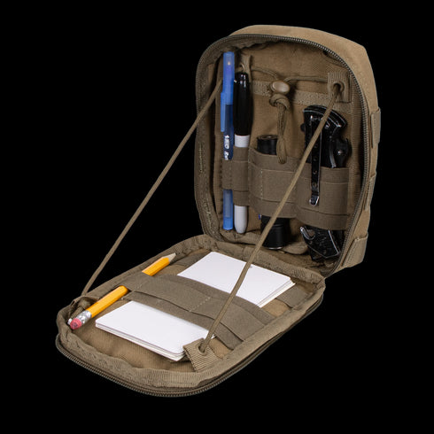 The Condor Sidekick Pouch in khaki opens to reveal pens, a flashlight, a multitool, a whistle, a pencil, and a notepad neatly secured with interior elastic straps.