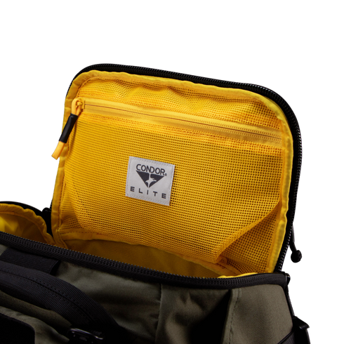 The Nomad Backpack 25L by Condor features a black and olive green exterior, an open view of its yellow mesh zippered pocket, and a signature Condor Elite label.