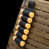 The Condor TSRS Shotshell Strip is a black elastic holder that attaches to tactical vests, securing seven orange shotgun shells—perfect for law enforcement or shooting range use.