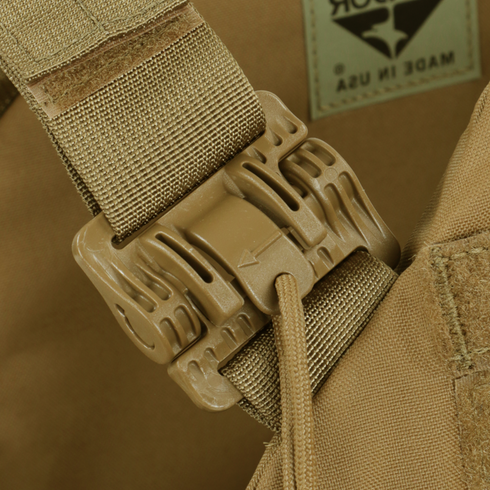 Close-up of a tan plastic buckle on the Condor Cyclone RS Plate Carrier - MultiCam Black, secured to a nylon strap, with part of a Made in USA label visible in the background.