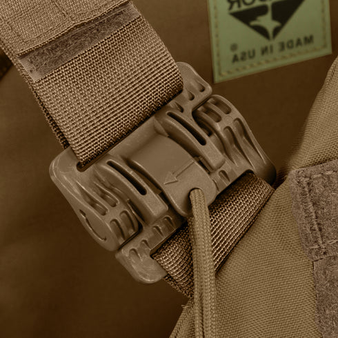 Close-up of a tan buckle fastener on a fabric strap, attached to brown material with visible stitching and a Made in USA label—part of the Condor Cyclone RS Plate Carrier, perfect for EDC or bushcraft gear.