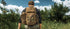 A person outdoors with a Condor Field Pouch | SALE, facing dense green bushes and a partly cloudy sky.
