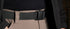 Close-up of a person wearing khaki pants and a Condor PDQ Magnetic Belt | SALE with a plastic buckle, paired with a black shirt and partially covered by a black jacket.