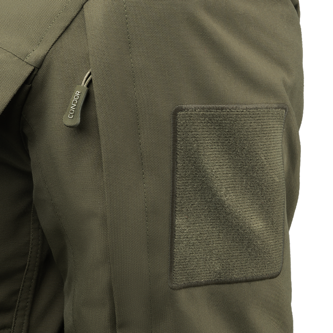 Close-up of an olive green Aegis Waterproof Parka pocket featuring a zipper pull labeled Condor and a large rectangular Velcro patch.