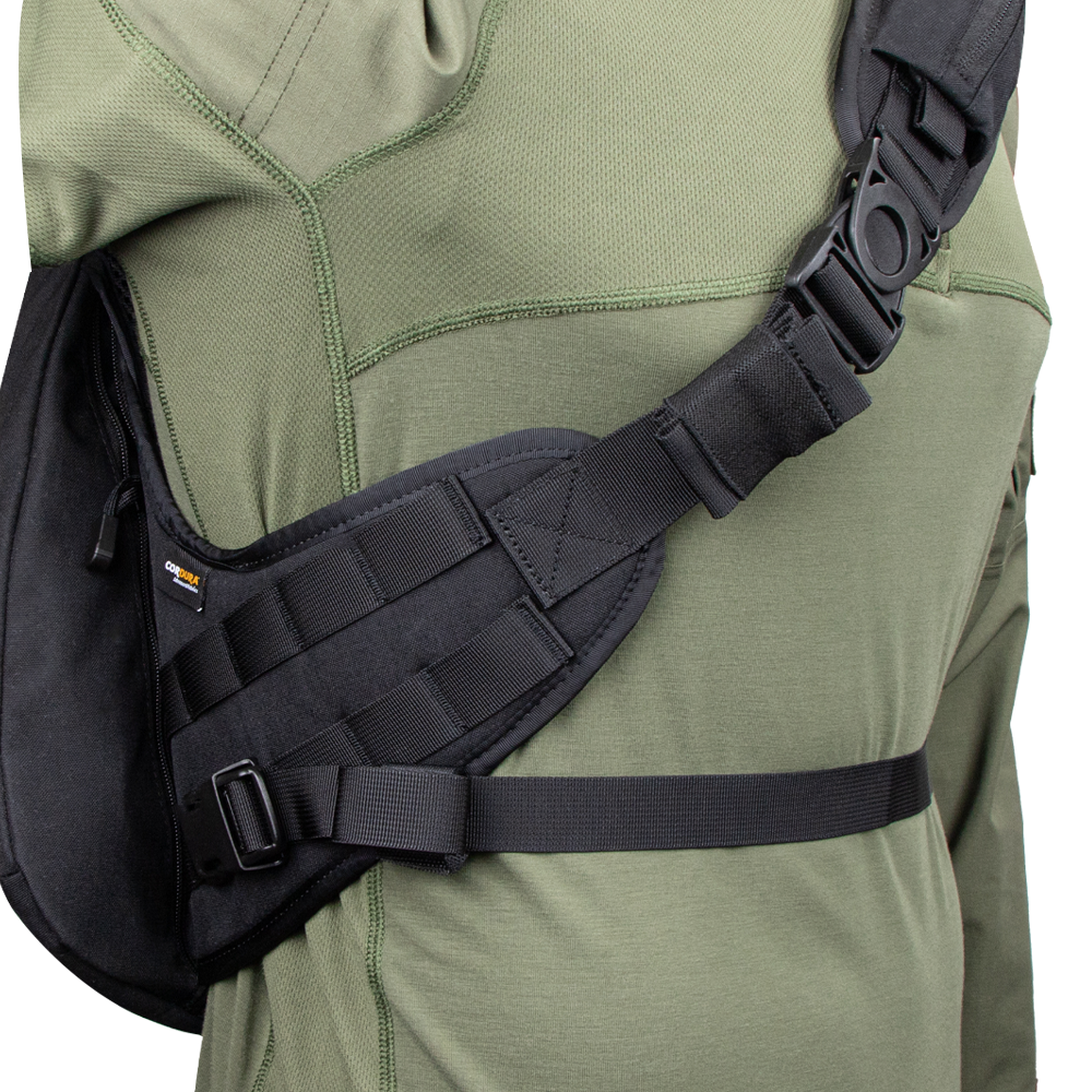 A close-up of a person wearing the Condor Elite Sector Sling Bag 18L by Condor, featuring black tactical straps with clips and padding, over an olive green long-sleeve shirt.