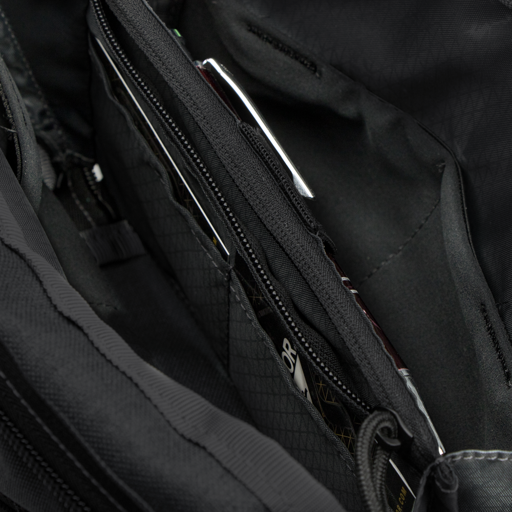Close-up of the Condor Tech Pouch in MultiCam Black, displaying multiple zippered compartments and pockets with partially visible items inside.